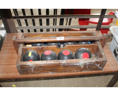 A wooden box containing two sets of four small carpet bowls