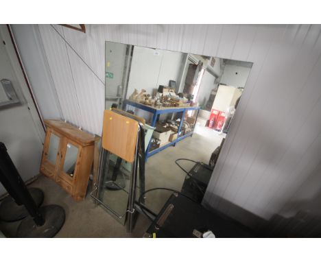 A large unframed wall mirror, another and a projector stand