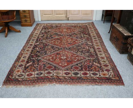 Khamseh Carpet, the indigo field with three hooked diamond medallions surrounded by tribal motifs, enclosed by ivory borders,