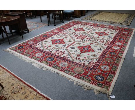 An Indian Carpet, the ivory stepped lattice field enclosed by crimson borders, 370cm by 290cm