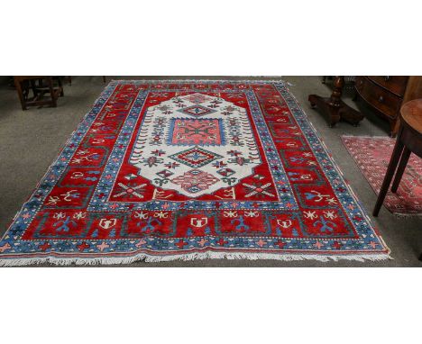 Turkish Carpet, the ivory lozenge field of geometric motifs framed by wide blood-red borders, 320cm by 237cm