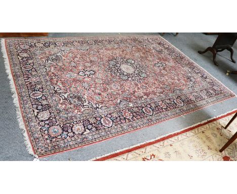A Kashmir Silk Carpet, the coral pink field of vines centred by a medallion framed by spandrels and indigo borders, 273cm by 