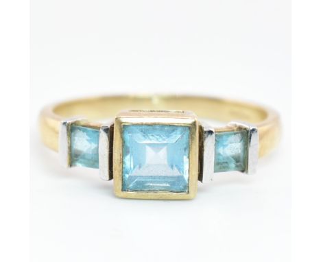 A hallmarked 9ct gold and topaz three stone ring. The 9ct yellow gold ring set with a central bezel set square step-cut topaz