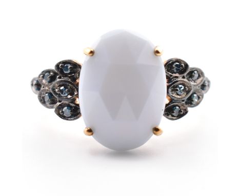 A hallmarked 9ct gold Jacui blue opal and blue diamond ring. The ring set with a central oval fancy cut Jacui blue opal to de