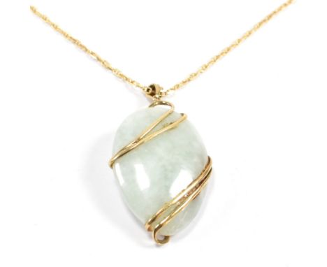 A 9ct gold and jade pendant strung on an 18ct gold necklace chain. The hallmarked 9ct gold and jade pendant strung on an 18ct