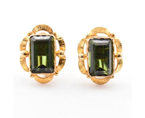 A pair of 9ct gold and green tourmaline earrings. The earrings having a step-cut tourmaline to scalloped mount with screw-bac