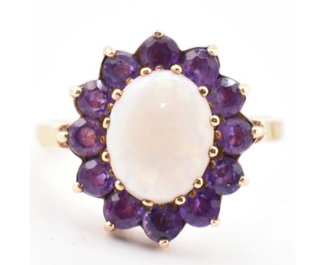 A hallmarked 9ct gold, opal and amethyst cluster ring. The ring having a central oval opal cabochon surrounded by a halo of r