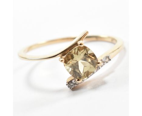 A hallmarked 9ct gold, epidote and spinel crossover ring. The 9ct yellow gold ring having a cushion cut epidote in a crossove