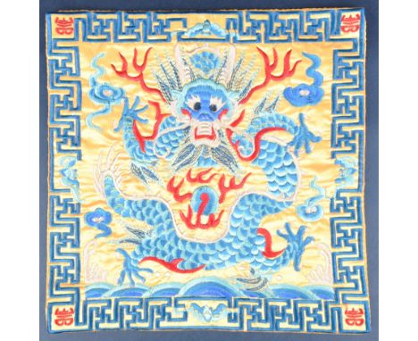 A 20th Century Chinese embroidered silk rank patch rank square. Yellow ground with vibrant blue dragon and ochre flaming scro
