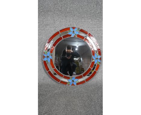 A vintage round stained glass wall mirror with red and black panels and four pale blue flower motifs. H.63 W.60 