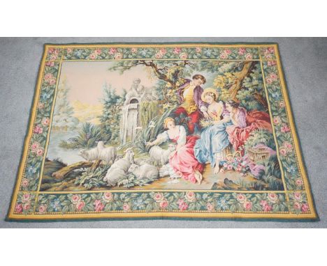 A vintage Aubusson style tapestry wall hanging depicting a garden with people by a lake with sheep surrounded by a floral and
