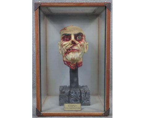 A vintage plastic and plaster painted zombie head on a concrete effect stand housed within a bespoke display case. Plaque rea