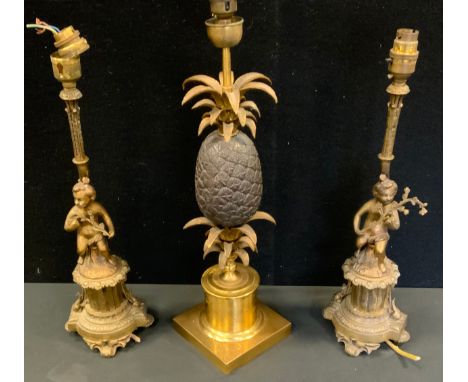 A Maison Charles style gilt and bronzed metal pineapple table lamp, 51cm high;  a pair of cherub lamps, 44.5cm high (3) 