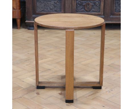 An Art Deco oak coffee table, having a circular top raised on four shouldered planar legs united at floor level by a conformi