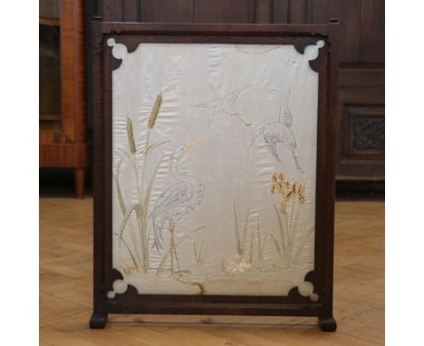 A late 19th / early 20th Century Gothic-influenced carved-oak fire screen, having an embroidered insert depicting storks amon