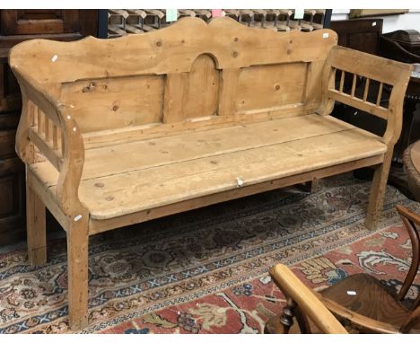 A pine bench with panelled back and galleried arms over a two plank seat on square legs 179 cm wide x 53 cm deep x 114 cm hig