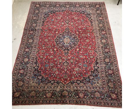 A Kashan carpet, the central panel set with floral decorated medallion on a red scrolling floral decorated ground, within a s