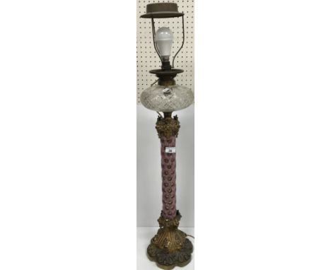A Victorian gilt bronze mounted table oil lamp with brass fittings and hobnail cut glass reservoir on a pink overlaid cut gla