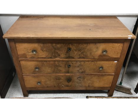 A 19th Century French walnut commode, the plain top over three figured drawers with pressed brass handles, raised on heavy sq