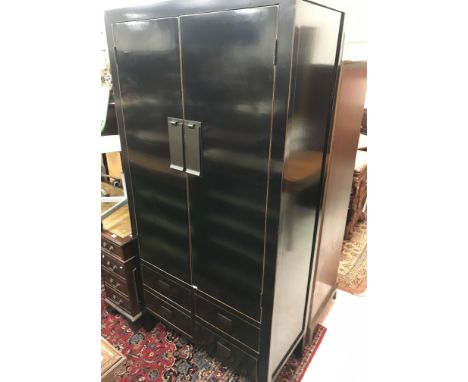 A modern black lacquered wardrobe in the Japanese taste, the two large cupboard doors enclosing a shelf and hanging space, ov