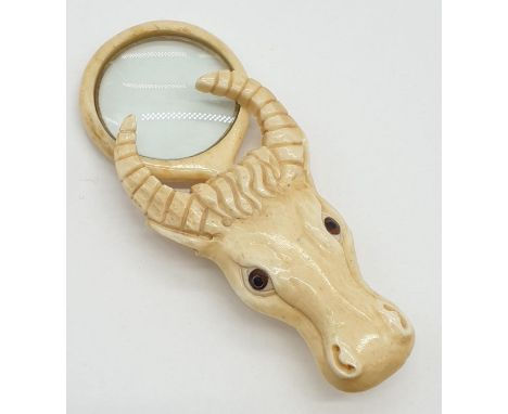 A vintage bone magnifying glass attached to a bone bull's head. 