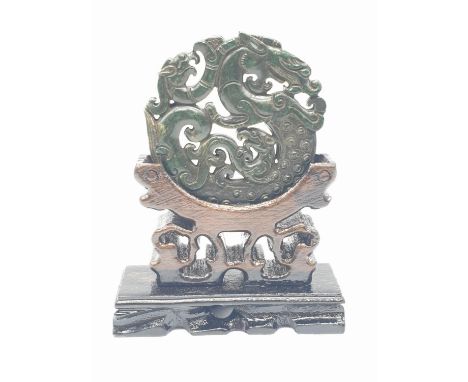 A Chinese, hand carved on both sides and pierced, dark green jade amulet, representing mythical beasts on stylised clouds. Pr