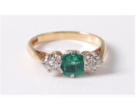 An emerald and diamond ring, the central emerald cut emerald set to either side with a round brilliant cut diamond, total est