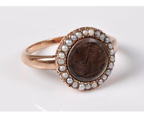 A 19th century split pearl and hairwork memorial ring, the central glazed panel with plaited hairwork below, surrounded by sm