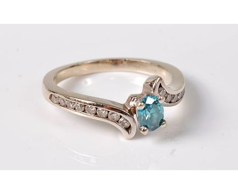 A treated blue and white diamond ring, the asymetrically set oval treated blue diamond, estimated approx. 0.45cts, set to eit