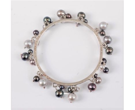 A silver and cultured pearl bangle by Dower & Hall, the 3mm wide bangle set with varying shades of grey pearls, ranging betwe