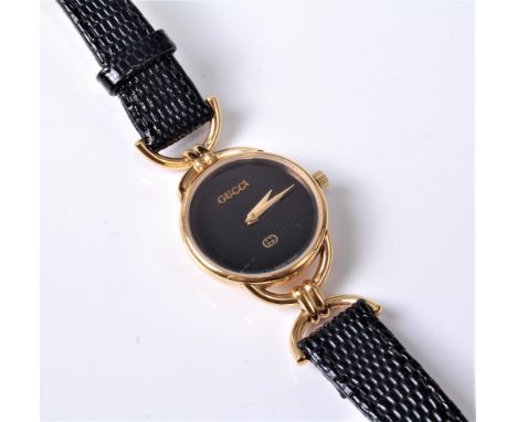 A lady's Gucci dress watch, the round black dial with gilt hands, in gilt metal case, 22mm diameter, with black leather case