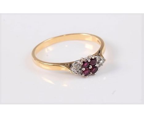 An 18ct ruby and diamond ring, the four round rubies set to either side with three small round diamonds, all set in white met