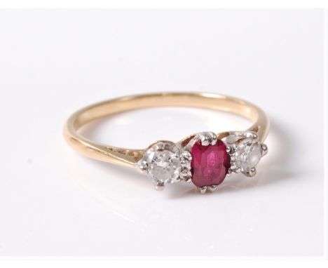 A three stone ruby and diamond ring, the central oval ruby set to either side with a round brilliant cut diamond, total estim