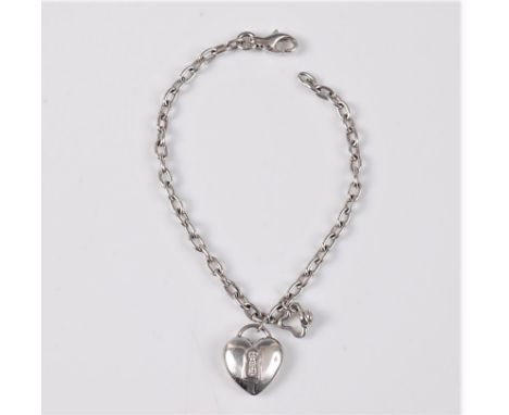 A diamond set heart shaped charm bracelet, the heart set with a keyhole containing three small diamonds, set to a plain brace