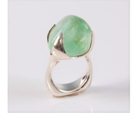 A contemporary fluorite ring, the natural form polished pale green fluorite, approx. 17mm wide, set in four large tapered cla