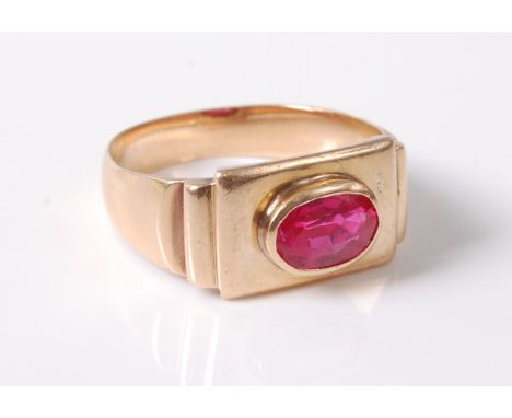 A synthetic pink sapphire ring, the oval pink sapphire in a rubover mount, set in a rectangular stepped plaque, with plain ta