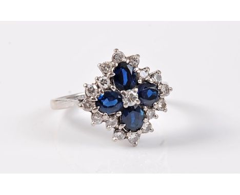 A sapphire and diamond ring, the central round diamond surrounded by four oval cut sapphires, all surrounded by a single row 