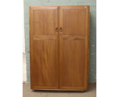 An Ercol chestnut double wardrobe fitted internally with a bank of four drawers.