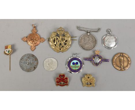 A box of badges, fobs and coins, including silver and enamel examples.