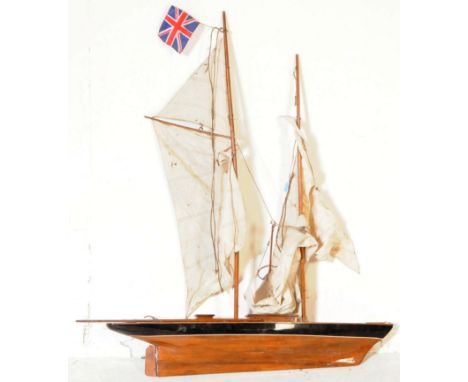A vintage late 20th century sailing boat / yacht. With curved varnish body with rudder, a series of sails and masts present b