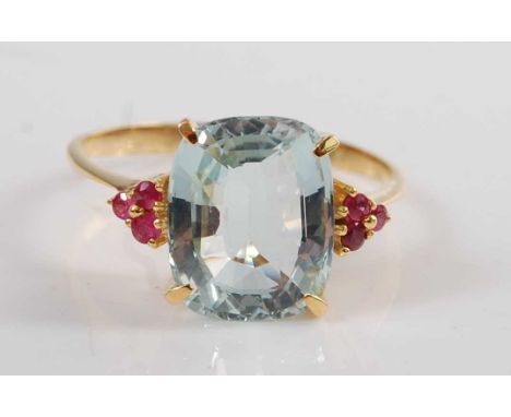 A yellow metal, aquamarine and ruby dress ring, comprising a cushion shaped aquamarine in a four-claw setting, with a trefoil