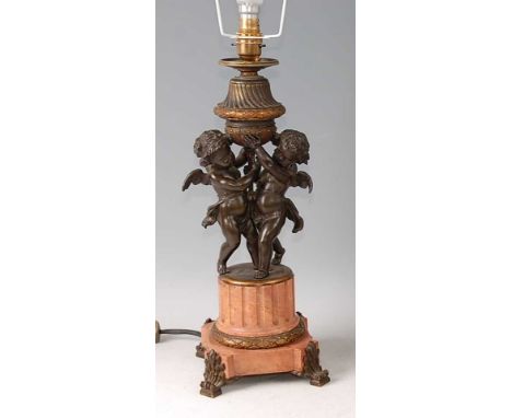 *A circa 1900 French bronze and marble table lamp, modelled as a pair of winged cherubs upon a fluted rouge marble plinth, th