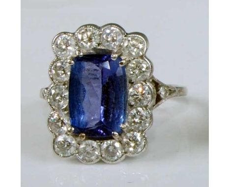 A white metal, tanzanite and diamond oblong cluster ring, featuring a centre oval tanzanite in a four double claw setting, wi