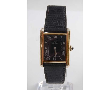 A silver gilt cased Must de Cartier tank quartz wristwatch, having rectangular black Roman dial and fitted to a black Cartier