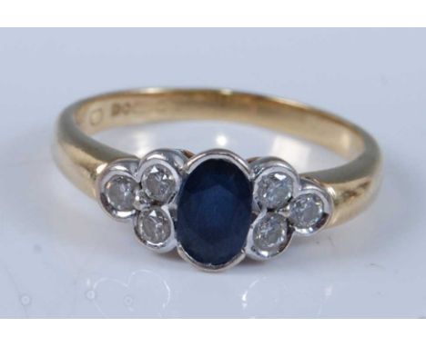 An 18ct yellow and white gold, sapphire and diamond ring, featuring a centre oval faceted sapphire with a trefoil of diamonds