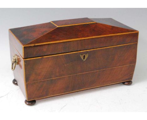 A Regency mahogany and boxwood strung tea caddy, of sarcophagus form, having partitioned interior and applied brass lion mask