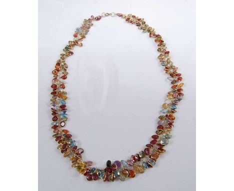 A yellow metal multi-stone fringe necklet, comprising oval faceted garnets, blue topaz, amethyst, citrine, peridot, tourmalin