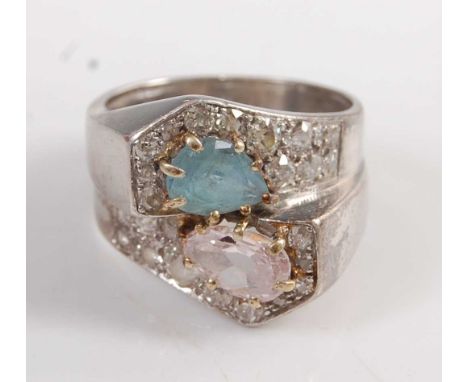 A white metal crossover ring, comprising a pear shaped aquamarine, a pear shaped pink sapphire, and 26 single and old Europea