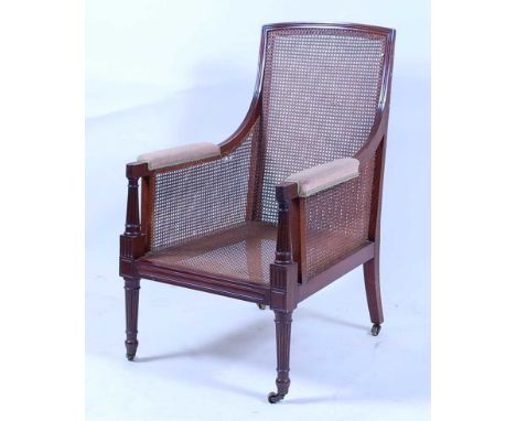 *A 19th century mahogany bergère library armchair, having single cane back, seat and sides, on turned and fluted supports, wi