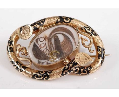 A late Victorian yellow metal mourning brooch, having a central oval panel with ornate hair detail and three seed pearls, wit